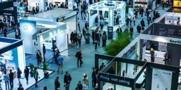 This photo captures the dynamic atmosphere of a trade show in full swing, showcasing an array of exhibitors and attendees. Under the bright lights of the venue, businesses and industry professionals gather to display their latest offerings, share insights, and create valuable connections. The strategic layout of the booths enhances visibility and facilitates interaction, making it an ideal environment for networking, learning, and fostering growth opportunities within the industry.