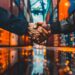 In this striking image, a moment of business agreement or partnership is captured through a handshake that seamlessly merges with the industrial setting of a shipping yard. Rows of vibrant and towering shipping containers frame the handshake, emphasizing the scope and significance of the agreement being forged. The reflection on the water's surface adds a layer of depth and symmetry, hinting at the thoughtful consideration and mutual respect that underpins such an exchange. The photo encapsulates not just a personal connection, but also the global scale of trade and commerce that relies on such individual moments of trust and collaboration.