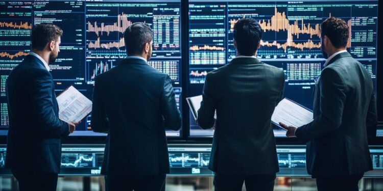 In a modern, high-tech trading floor environment, three financial professionals are deeply engaged in analyzing real-time stock market data displayed across several large screens. Each individual, clad in business attire, focuses intently on the fluctuating charts and graphs that depict various market trends and stock behaviors. They hold documents, likely containing additional detailed financial reports or historical data, which assist them in making informed decisions. The room is dimly lit, emphasizing the glowing screens and the serious, focused atmosphere of financial analysis and strategy.